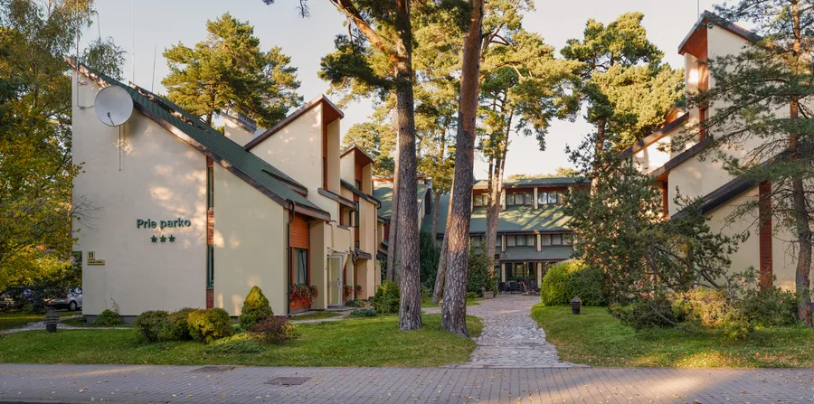 Panoraminis vaizdas į korpusus ir taką tarp pušų